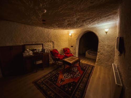 格雷梅Asteria Cave Hotel的洞穴内的房间,配有两张红色椅子和一张桌子