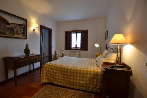 吉马良斯Quinta De Cima De Eiriz的一间卧室配有一张床和一张带台灯的桌子