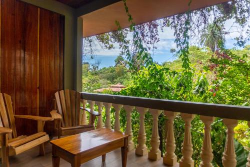 德雷克Jacamar Corcovado Drake Bay的阳台配有桌椅和大窗户。