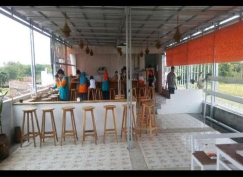 KlatenD'SAWAH GUESTHOUSE的酒吧设有木凳,一群人