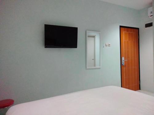 雅加达Pondok Indah24 Hotel的一间卧室配有一张床,墙上设有一台平面电视