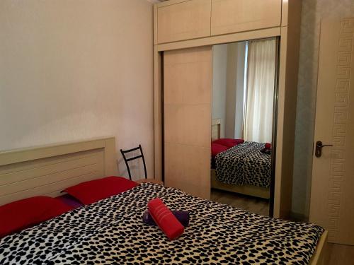 第比利斯tamunas apartment的一间卧室配有一张带红色枕头和镜子的床
