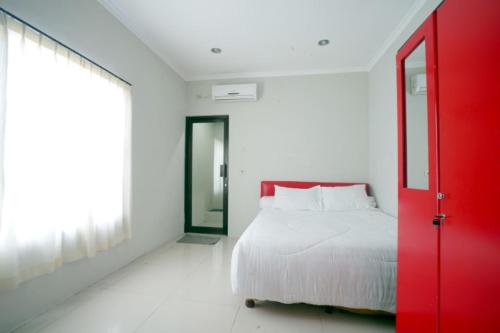 玛琅布吉特迪恩德帕拉贡旅馆的卧室设有红色门和白色床