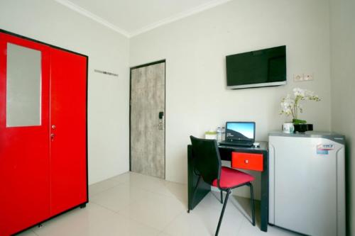玛琅布吉特迪恩德帕拉贡旅馆的一间设有一张桌子、一台电脑和一扇红色的门的房间