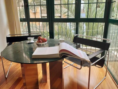 阿利坎特COLLECTION CITY - Bed & Breakfast, Alicante Center I Cocina & Amplia Terraza - Jardín的一张桌子,上面放着一本书和一碗水果