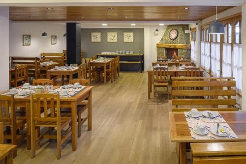圣马丁德洛斯Hotel Intermonti的餐厅设有木桌、椅子和壁炉