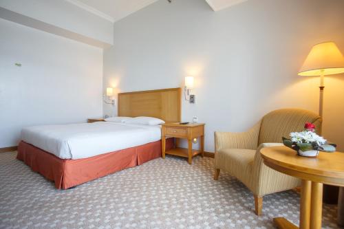 马尼拉The Linden Suites的酒店客房带一张床、一张桌子和椅子