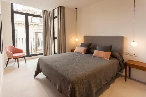 马拉加Apartamentos Málaga Premium - Calle Granada的卧室配有床、椅子和窗户。