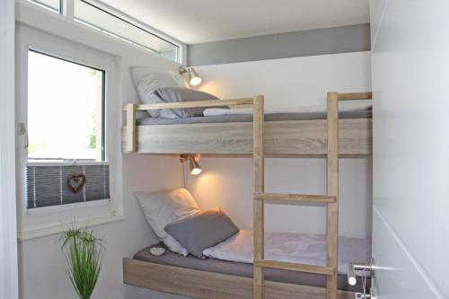 格吕克斯堡fewo1846 - StrandNest - luxuriöse Unterkunft am Strand mit 3 Schlafzimmern的客房设有双层床和窗户。