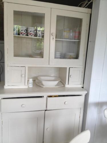 斯塔利格拉德-帕克利尼卡Petite house的厨房里设有玻璃门的白色橱柜