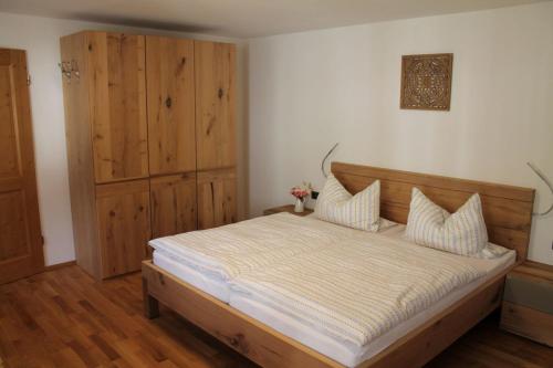 柯尼希斯湖畔舍瑙Pension Neuhausen的一间卧室配有一张大床和一个木制橱柜