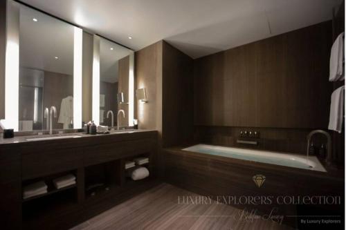 迪拜1BR Apartment at Armani Hotel Residence by Luxury Explorers Collection的一间带浴缸和大镜子的浴室
