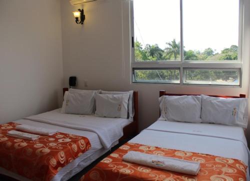 GuamalHotel Rio Humadea的带2扇窗户的客房内的2张床