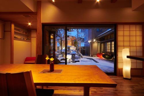 高山Ichinomatsu Japanese Modern Hotel的一间带木桌和窗户的用餐室