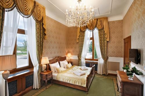 LubawaPałac Mortęgi Hotel & SPA的一间卧室配有一张床、吊灯和窗户。