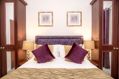 贝德格勒特皇家山羊酒店的一间卧室配有一张带紫色枕头的大床
