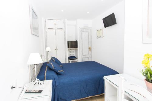 马贝拉Hostal La Estrella的一间白色客房内的蓝色床卧室