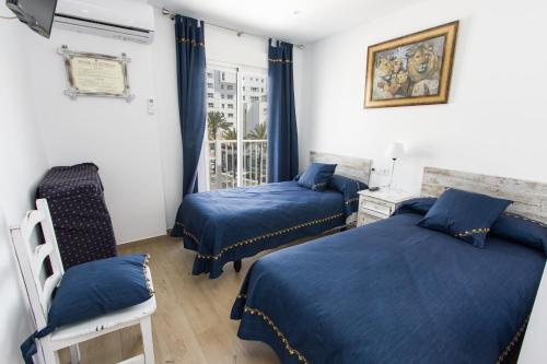 马贝拉Hostal La Estrella的配有两张床铺的蓝色床单和窗户