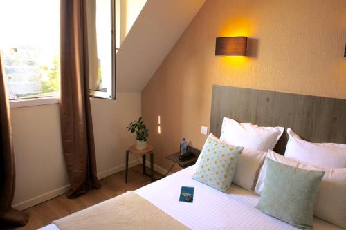 昂热Logis Hôtel Marguerite d'Anjou的卧室配有带枕头的床铺和窗户。