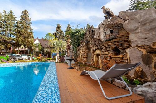 阿德勒Грейс Кристалл Отель的一座房子旁的游泳池,设有岩石墙