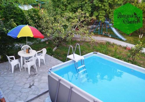 AshtarakAshtarak Garden GuestHouse的一个带桌子和遮阳伞的庭院,毗邻一个游泳池