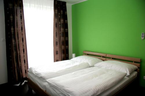 马拉茨基精致餐厅公寓的绿色卧室内的一张床位,设有窗户