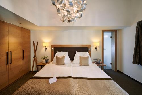 采尔马特安比安斯超级酒店的一间卧室配有一张大床和一个吊灯。