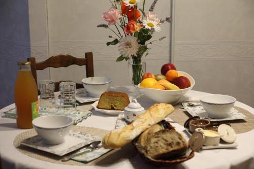 Saint-Ouen-des-ToitsChambre d hote La Roussiere的一张桌子,上面放着一盘面包和一碗水果
