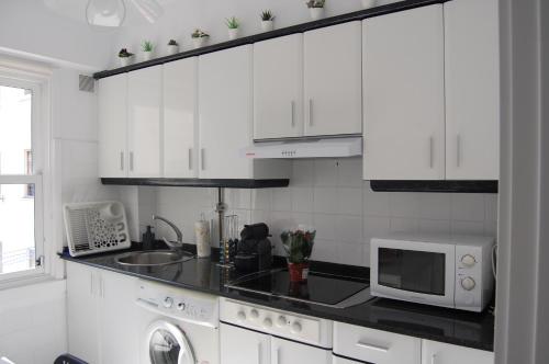 拉科鲁尼亚El Apartamento de Marta的白色的厨房配有微波炉和水槽