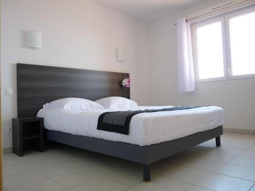 伊斯特尔普罗旺斯旅游酒店的一间卧室配有一张大床和木制床头板