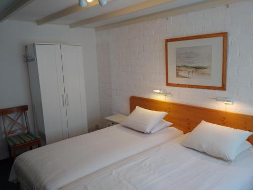 尼乌弗利特樱桃园酒店的卧室内配有两张白色的床,墙上挂着一幅画