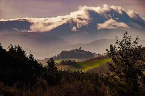 PeglioLa vedetta del Montefeltro的享有多云天山丘上城堡的景色