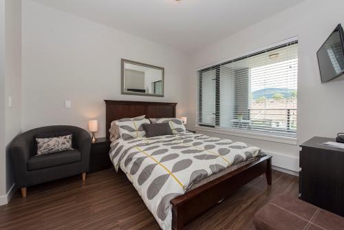 北温哥华Lower Lonsdale Aprtment的卧室配有床、椅子和窗户。