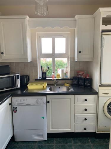 巴林罗布Mayfield House Holiday home的厨房配有白色橱柜、水槽和窗户。
