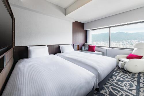 神户remm plus Kobe Sannomiya的酒店客房,配有两张床和椅子