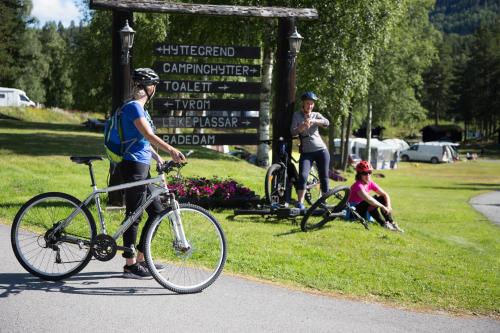 ÅmotGroven Camping & Hyttegrend的手持自行车的人在标志前