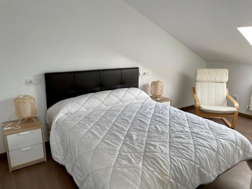 波尔托马林Alojamientos con encanto Ruliña的卧室配有一张白色大床和一把椅子