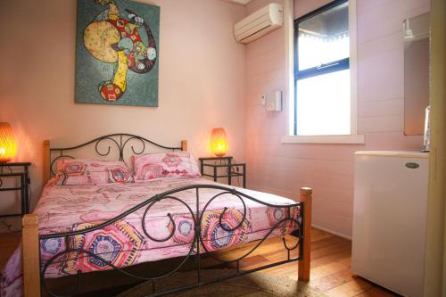 凯恩斯Dreamtime Travellers Rest的一间卧室配有一张带粉色床单的床和一扇窗户。