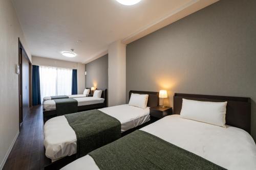大阪Hotel Piacere NAMBA的一间酒店客房,房间内设有三张床