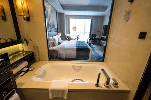 济宁济宁富力万达嘉华酒店的带浴缸的浴室和卧室