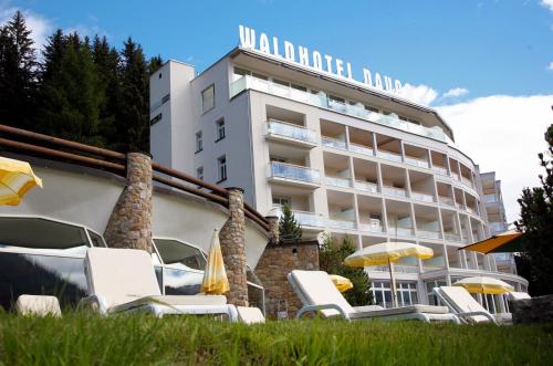 达沃斯Waldhotel & SPA Davos - for body & soul的大楼前的带椅子和遮阳伞的酒店