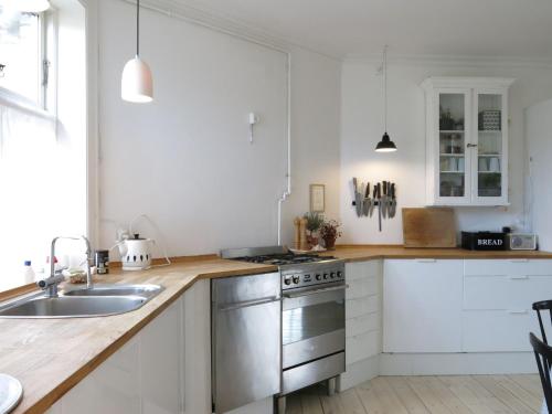 哥本哈根哥本哈根1159公寓的厨房配有白色橱柜和不锈钢炉灶。