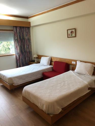 曼瓜尔迪HOTEL CRUZ DA MATA的酒店客房,设有两张床和一张红色椅子