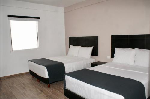 蒙克洛瓦Hotel Capital Frontera的酒店客房设有两张床和窗户。