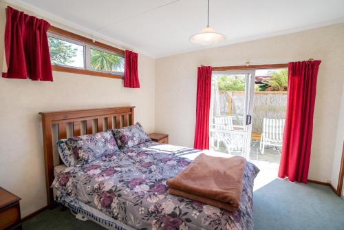 蒂阿瑙Dee's on Bligh - Te Anau Holiday Home的一间卧室配有床和红色窗帘的窗户