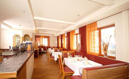 萨尔巴赫Hotel Sommerer - inklusive JOKER CARD im Sommer的餐厅设有白色的桌椅和窗户。