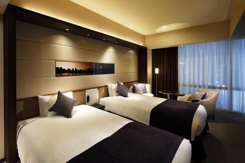 东京银座索拉里亚西铁酒店的酒店客房,配有两张床和椅子