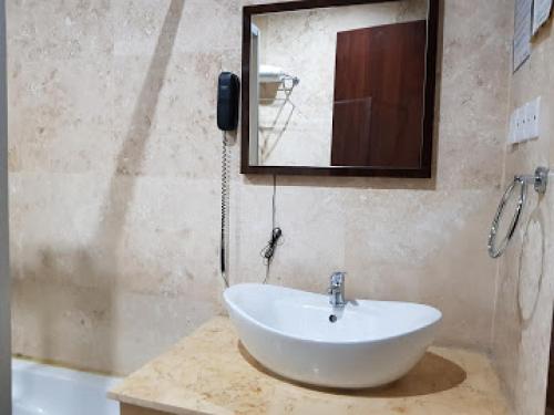 奥韦里Room in Lodge - Full Moon Hotel Owerri的浴室设有白色水槽和镜子