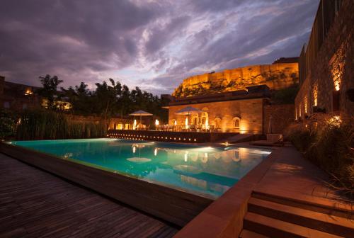 焦特布尔焦特布尔RAAS酒店的一座游泳池,在晚上在建筑物前
