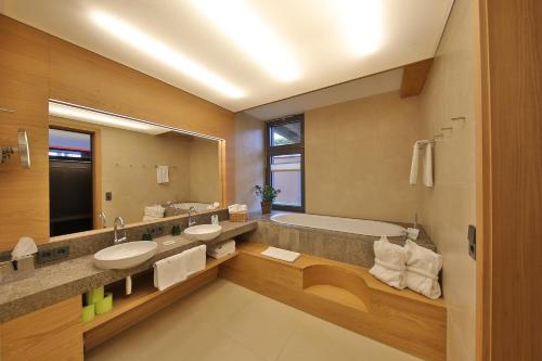 兰根堡玛威尔度假村的浴室设有2个水槽、浴缸和镜子